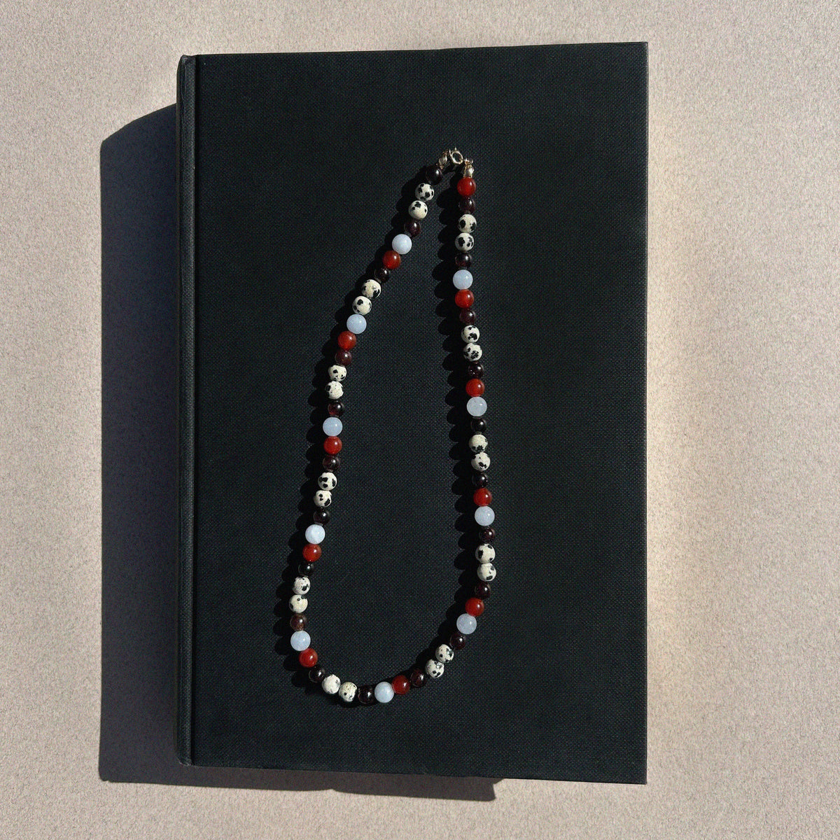 Paloma Gemstone Bead Necklace - flat lay styled shot on black book showing full multi-coloured gemstone strand | Token & Pearl